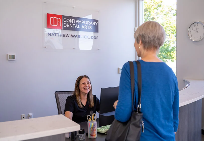 Senior female patient at the front desk to Tulsa Family Dental speaking with the staff about membership plans in Tulsa OK.
